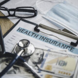Stethoscope and calculator placed on health insurance documents,